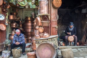 Marrakech vs Fes: A skilled artisan in Fes Medina handcrafting detailed copperware, a testament to the city's traditional craftsmanship.
